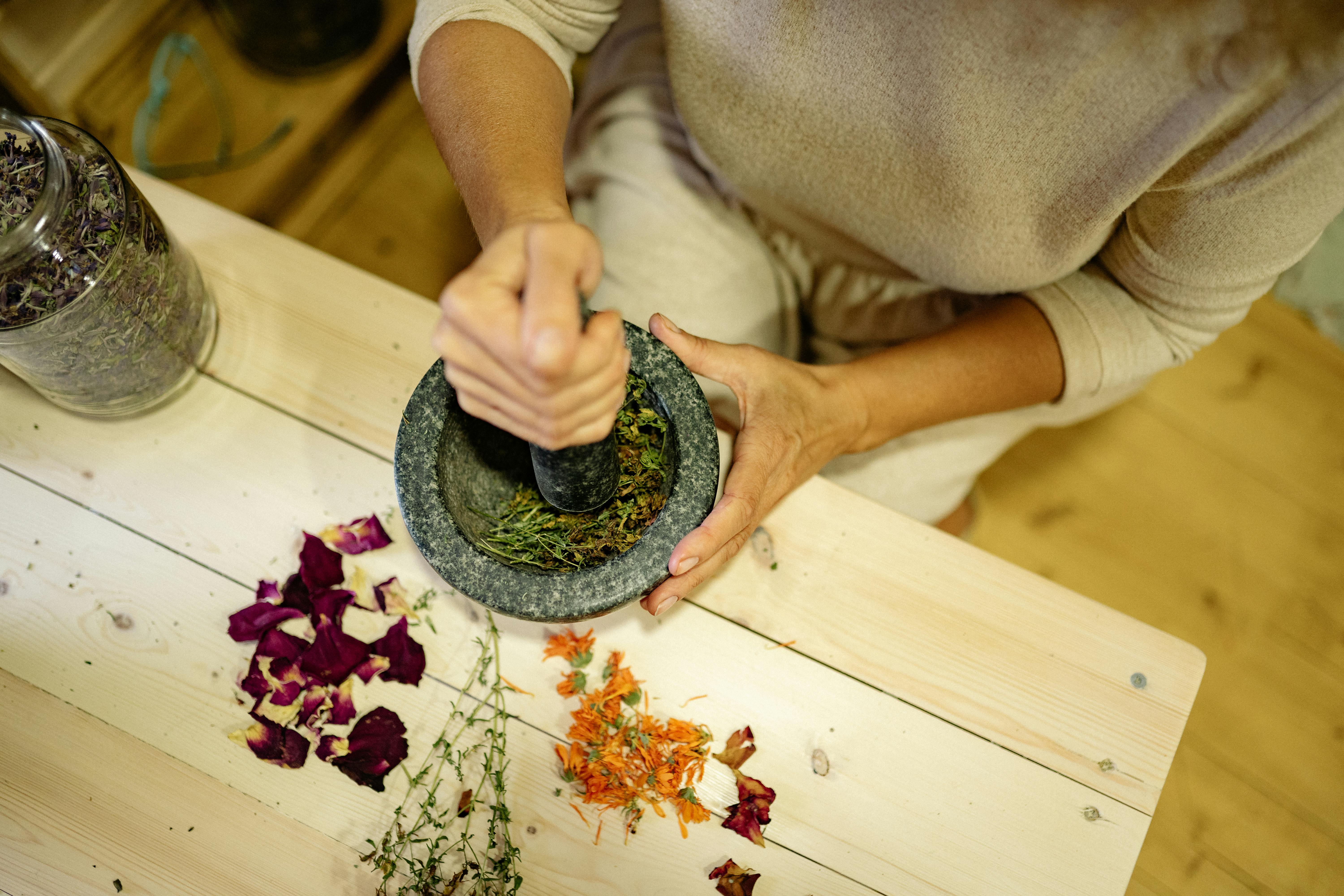 Hands grinding medicinal herbs with traditional mortar and pestle